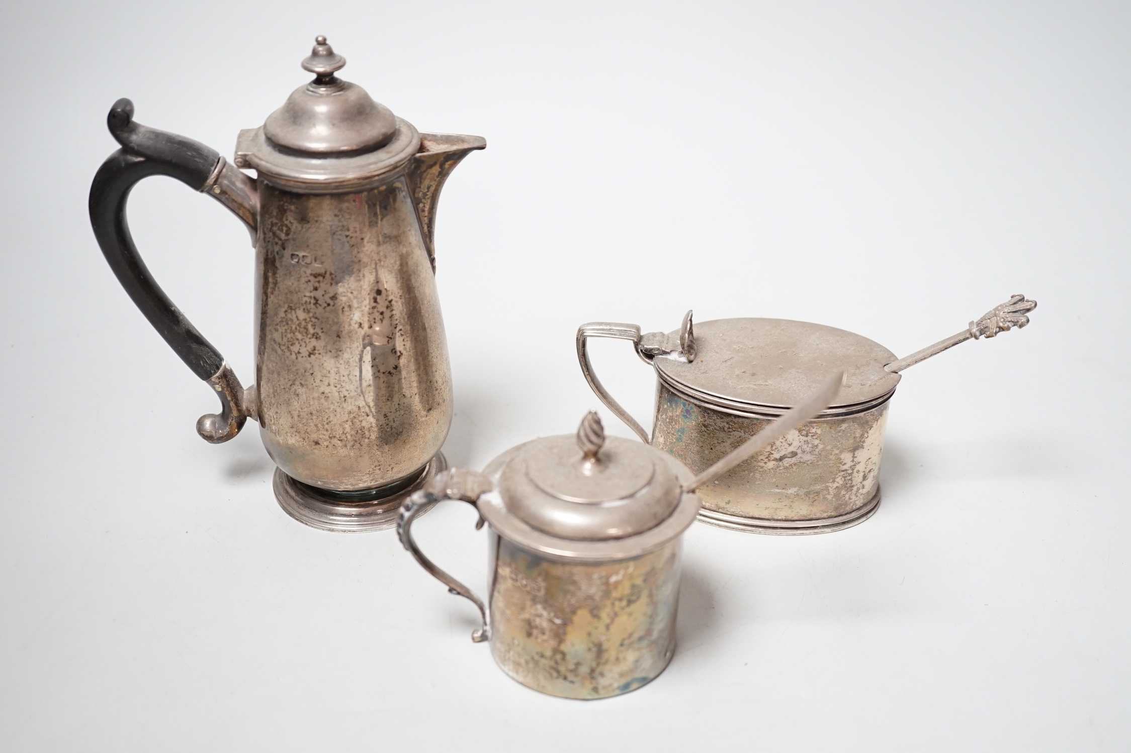 An early 20th century silver hot water pot and two silver mustard pots.